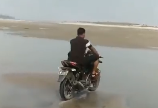 Homem tentando atravessa lago de moto